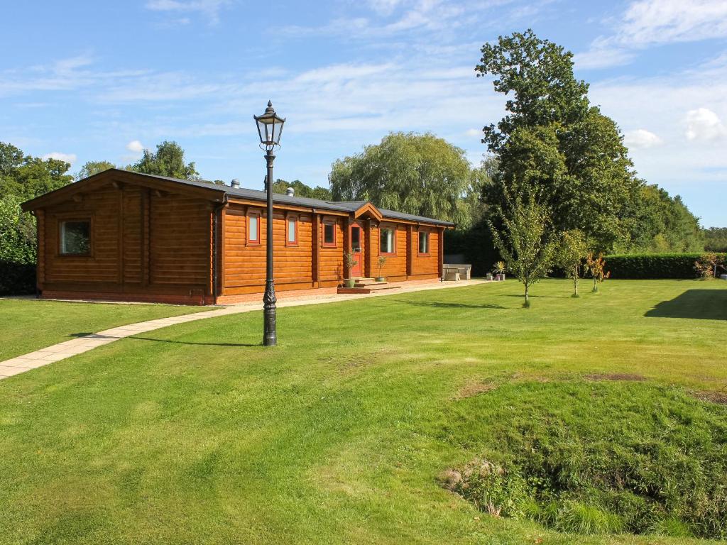 una cabina in legno con un palo della luce nell'erba di The Lodge a Storrington