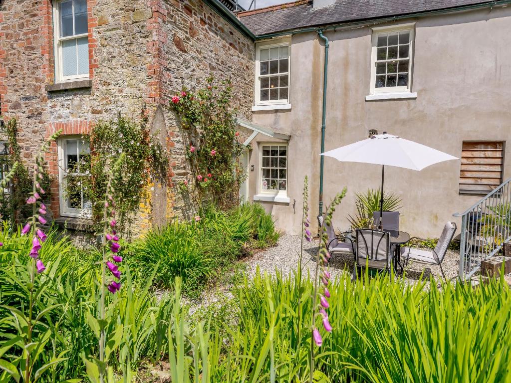 a patio with an umbrella in front of a building at South Wing Cottage in Rumleigh