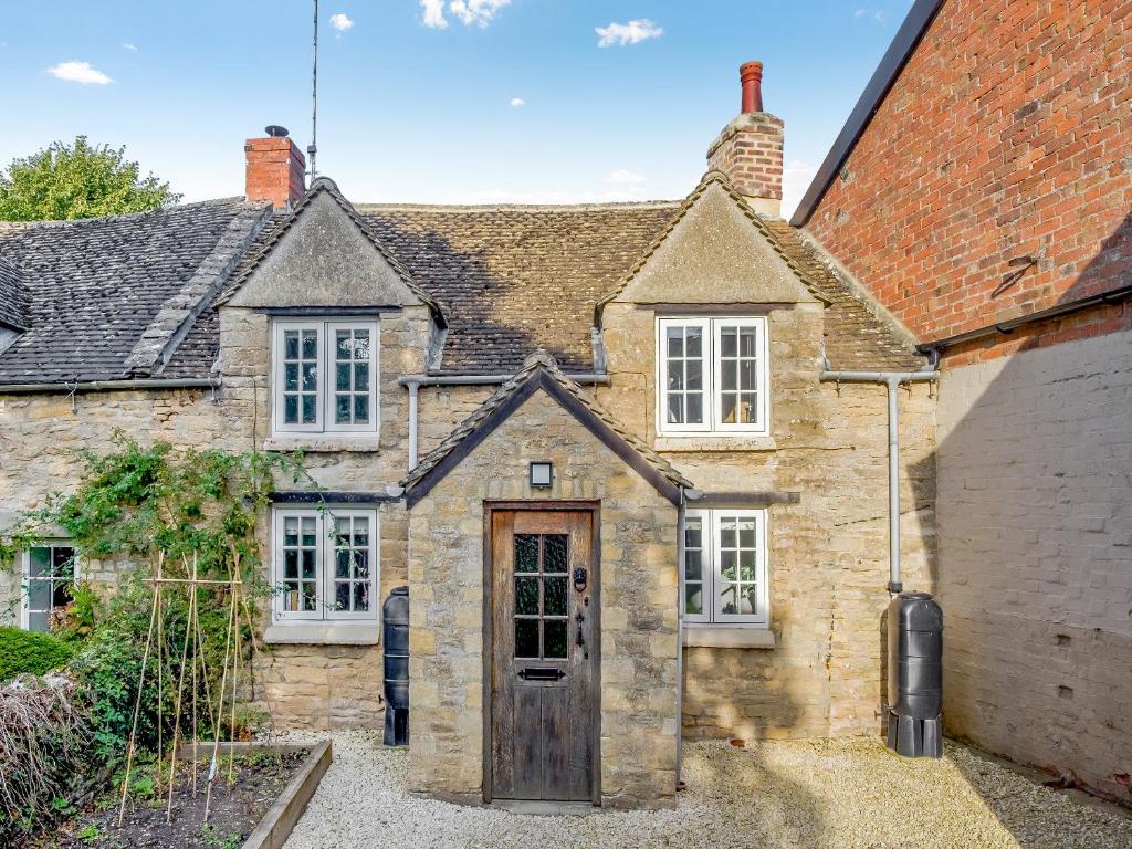 une ancienne maison en pierre avec une porte en bois dans l'établissement Patience Cottage, à Idbury