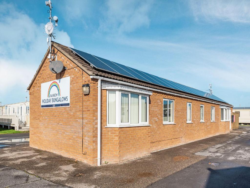 a red brick building with a sign on it at Rainbow Bungalow 1 - Uk39809 in Chapel Saint Leonards
