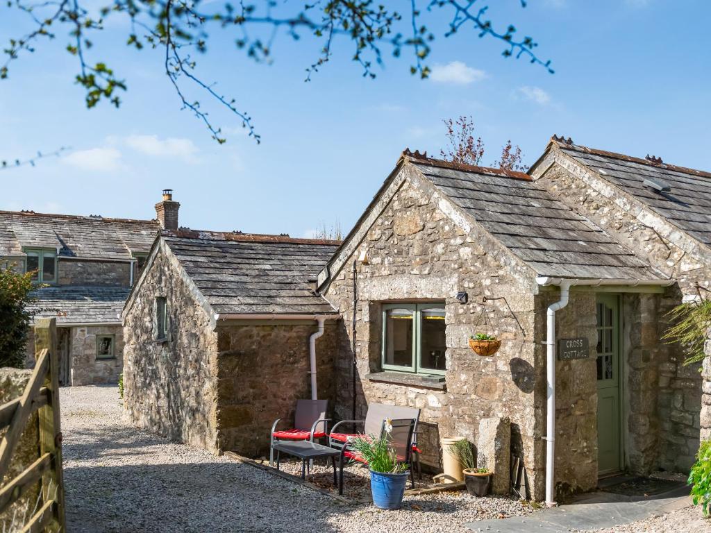 an old stone cottage with a red chair in front of it at Cross Cottage in Saint Breward