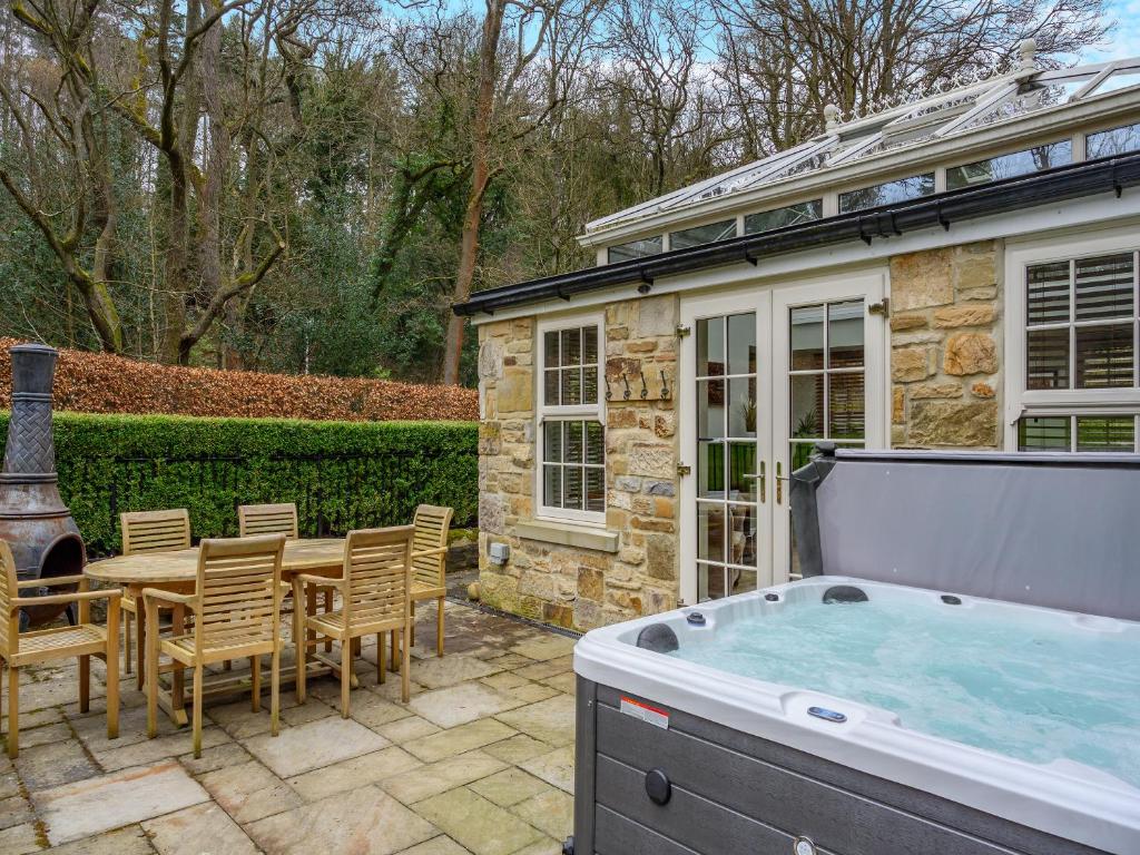 eine Terrasse mit einem Whirlpool, einem Tisch und Stühlen in der Unterkunft Cottage - Uk48472 in Lintz Green