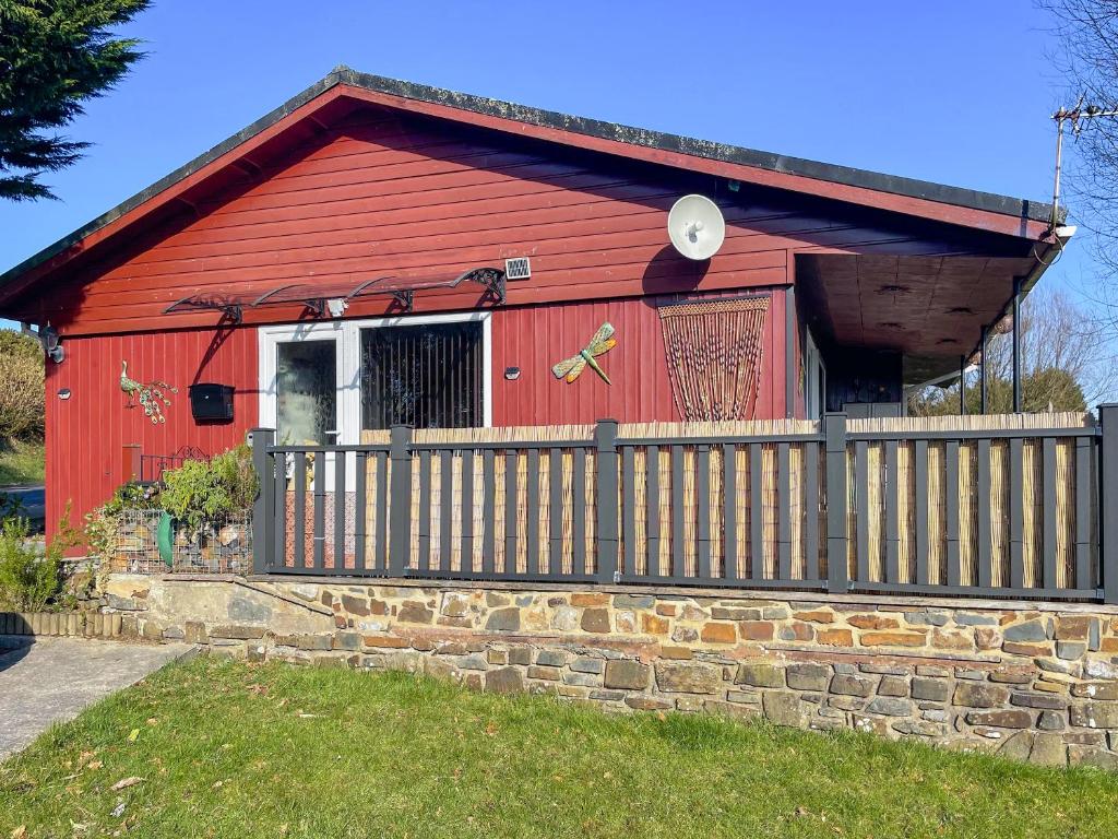un granero rojo con una valla delante en Valley View Lodge, en Bideford