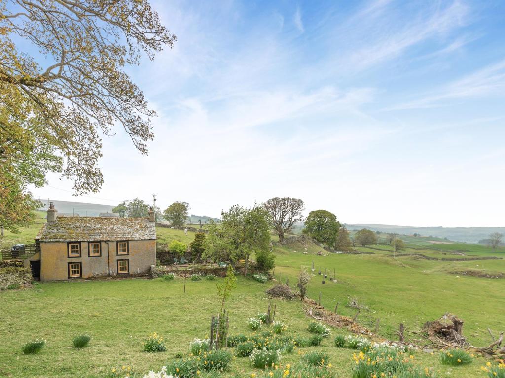 een oud huis in het midden van een veld bij Haweswater Cottage in Bampton