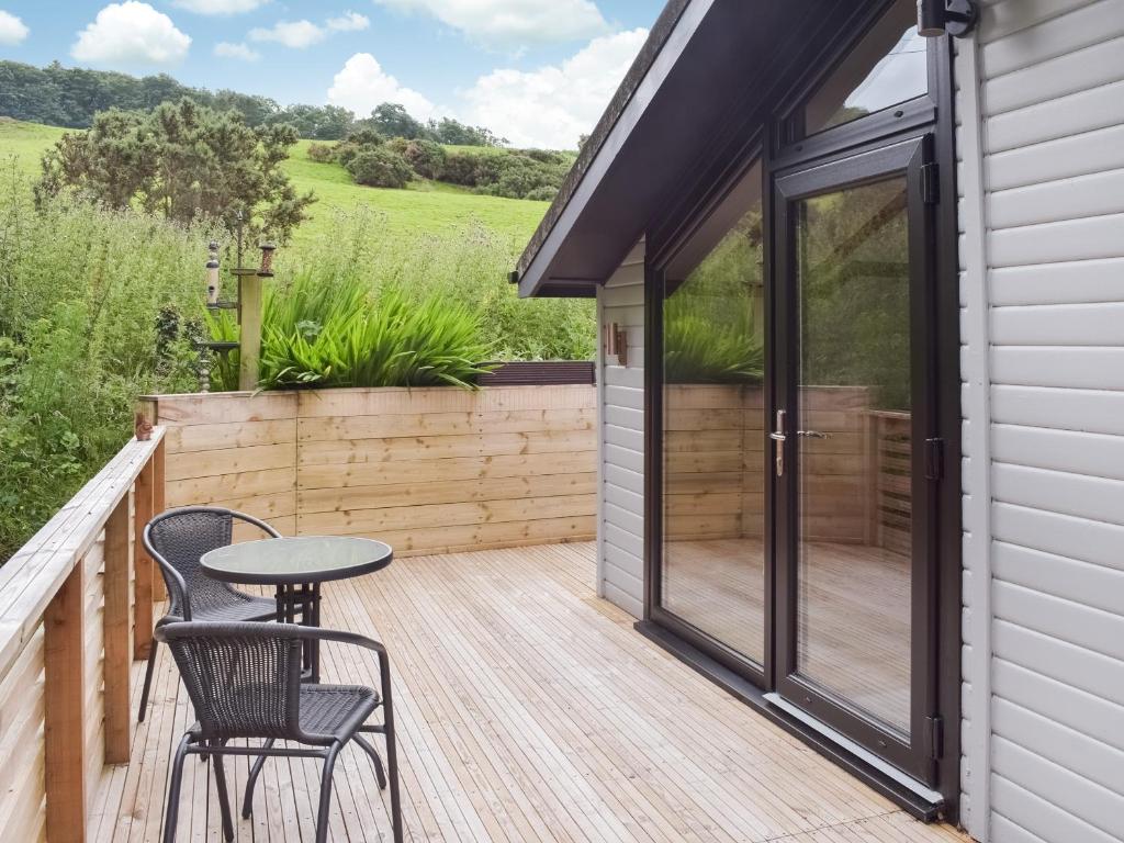 ColmonellにあるWoodlands Lodgeのデッキにテーブルと椅子が置かれたパティオ