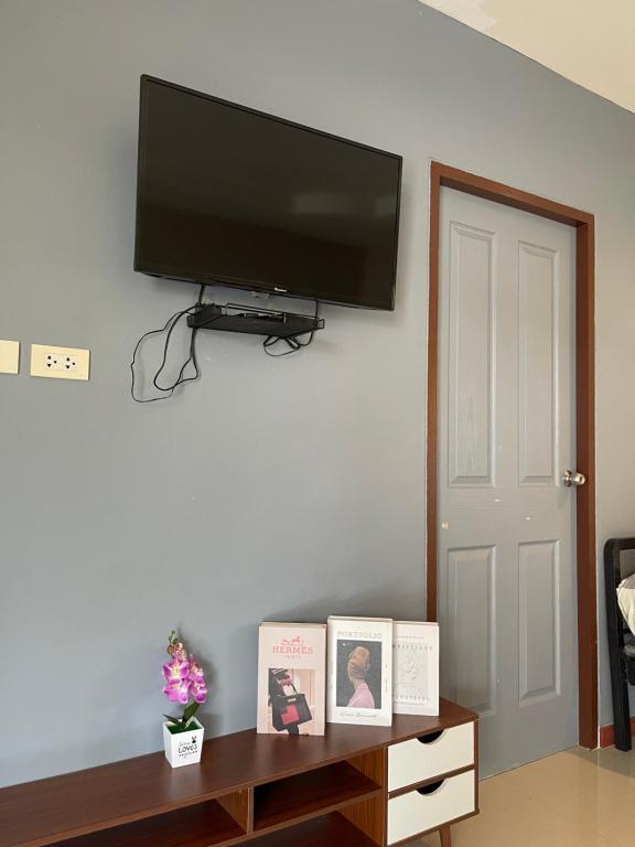 a living room with a flat screen tv on a wall at Pluemjai mansion in Ban Kathu