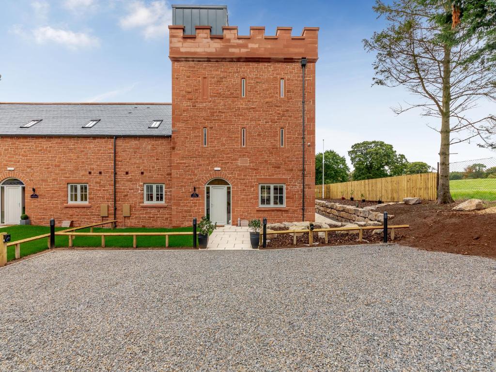a red brick building with a fence in front of it at Garth House - Peel Castle in Brampton