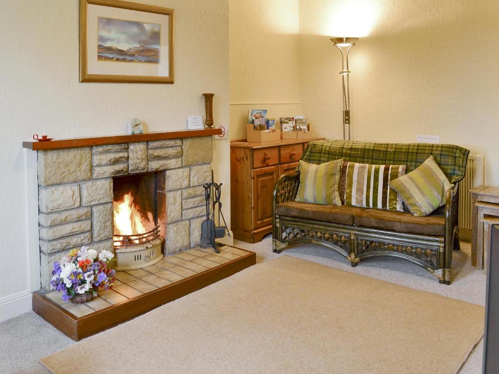 a living room with a couch and a fireplace at Blairhosh Cottage in Balloch