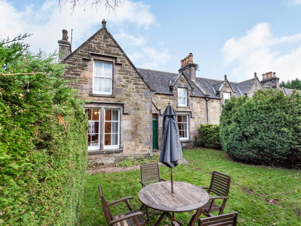 an umbrella sitting on a table in front of a house at Isla Bank Cottage in Keith