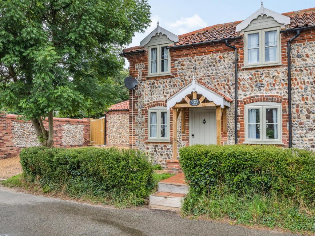 een oud bakstenen huis met een witte deur bij Clematis Cottage in Thorpe Market