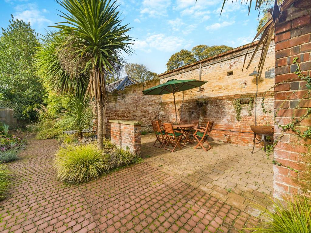 eine Terrasse mit Tisch und Sonnenschirm in der Unterkunft Blofield Cottage - Uk48095 in Norwich