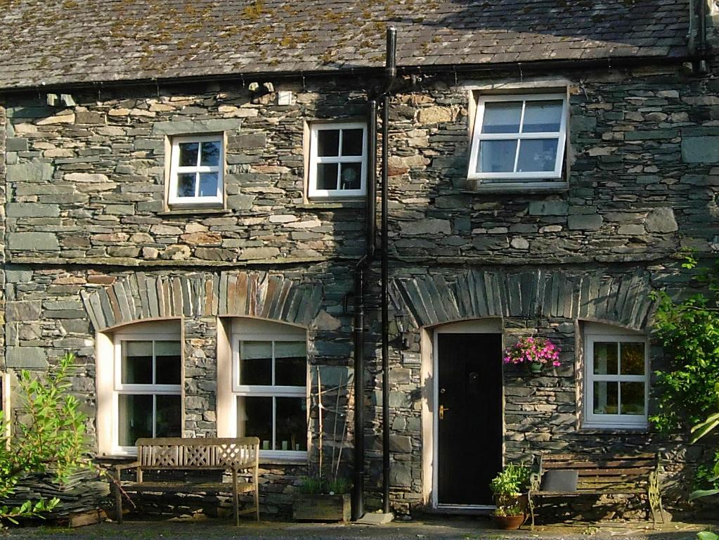 une maison en pierre avec un banc devant elle dans l'établissement Chapelfield Cottage, à Rosthwaite