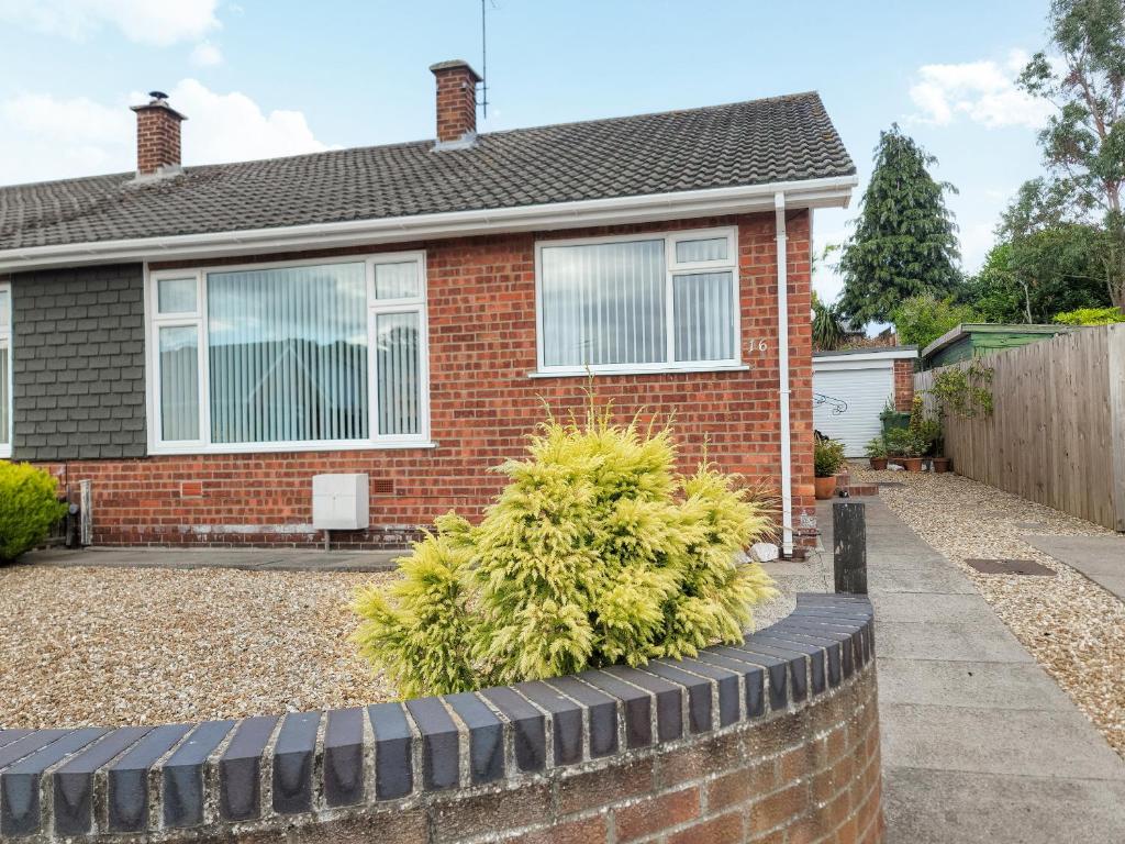 a red brick house with a garden in front of it at Driftwood Cottage in Sewerby
