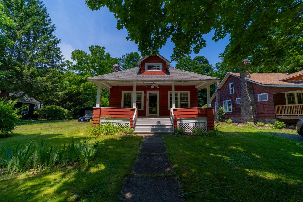 a red house with two benches on a lawn at 1920s Phoenicia Bungalow with Vintage Furnishings, Sauna, Fireplace, & Fenced Backyard in Phoenicia