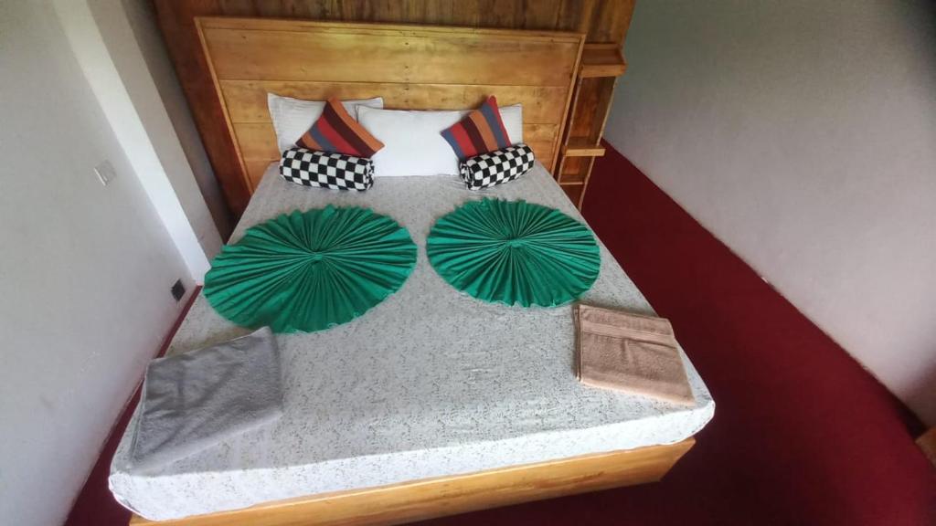 Una cama con cuatro sombrillas verdes encima. en River Resort Kitulgala, en Kitulgala