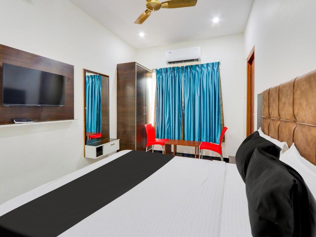 a bedroom with a bed and a tv and chairs at Hotel O Arjun Residency in Khammam