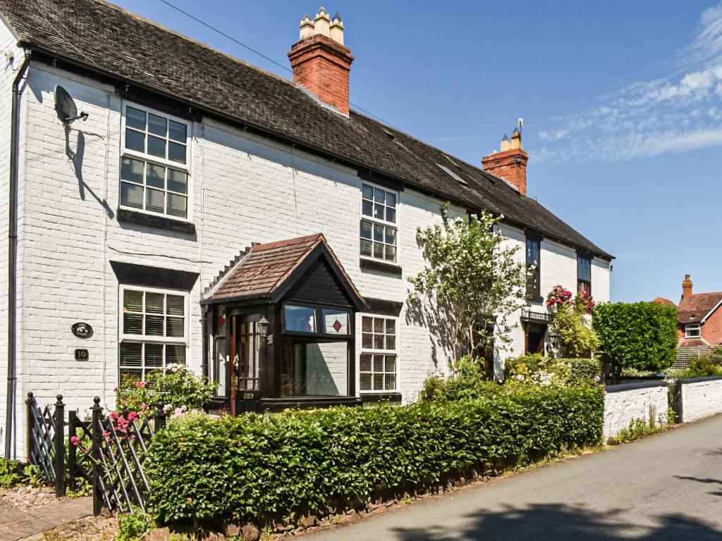 a white brick house with a black roof at Tansey Cottage in Hartlebury