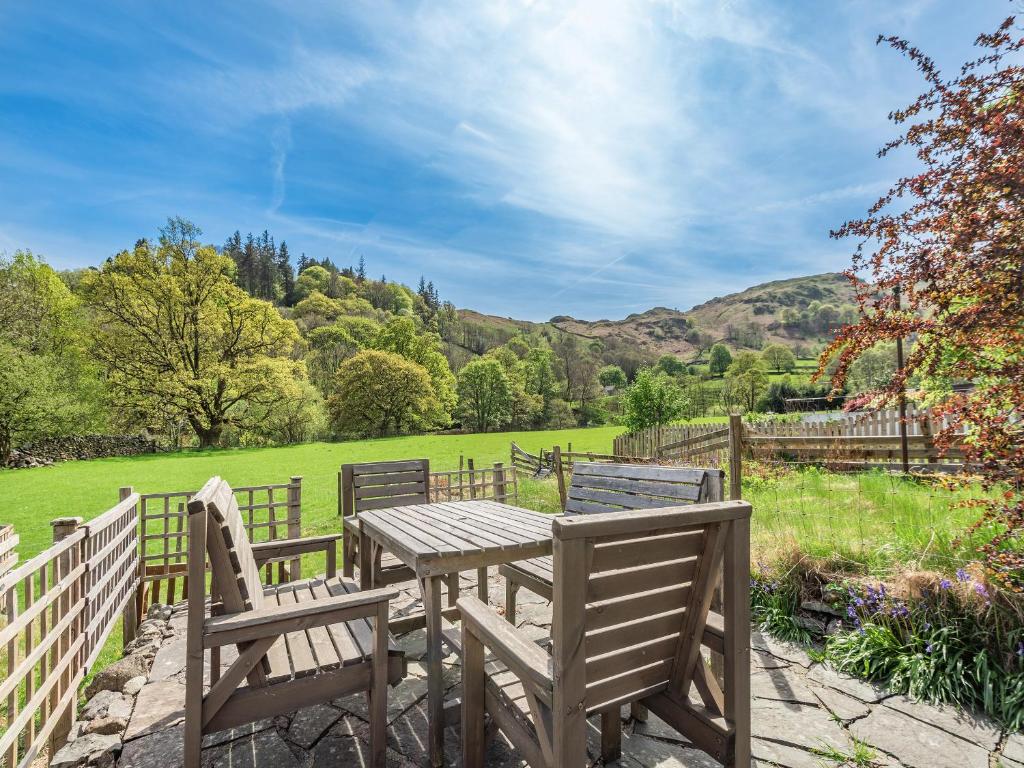 a wooden table with two chairs and a fence at Stybarrow View Cottage in Glenridding