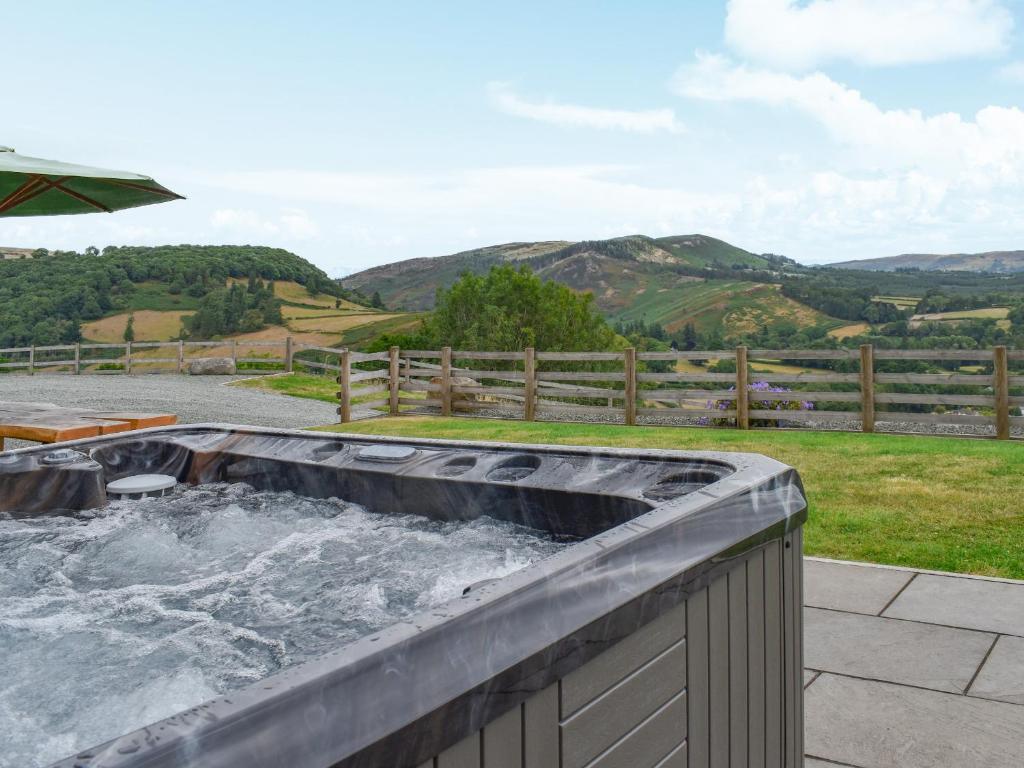 a hot tub with water in it on a patio at Pistyll Gwyn in Llanwrthwl