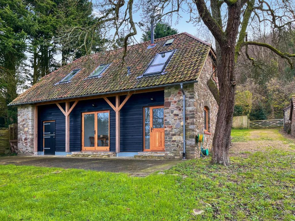 a small stone house with a tree in the yard at Walnut Cottage Barn in Clevedon