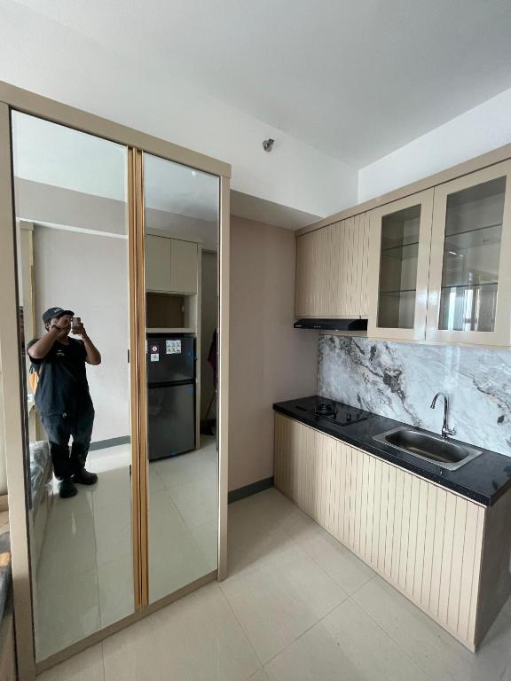 スラバヤにあるApartemen benson 21 pakuwon mall Luxury Studio Apartment Connecting Mall, Pool & City Viewの台所写真を撮る男
