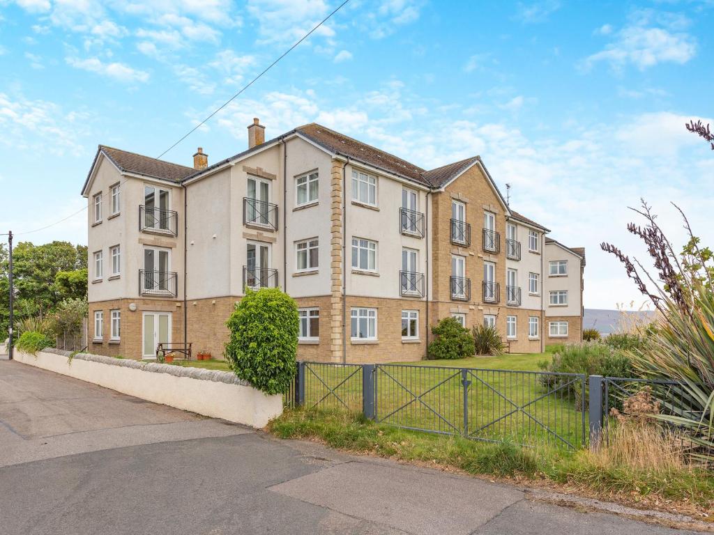 a large brick building with a fence in front of it at No4 The Links Apartments in Brora