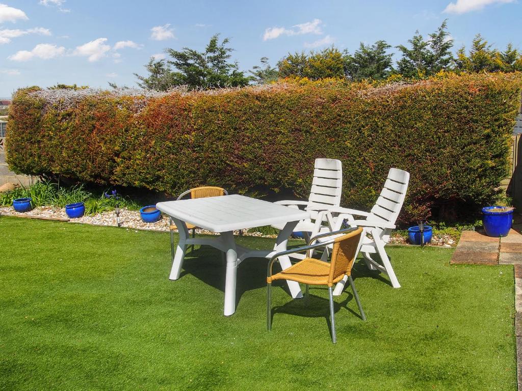 a white table and chairs on the grass at Seagull Cottage in Pagham