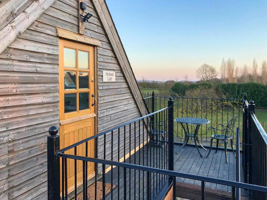 a cabin with a deck with a door and a table at Orchard Loft in Oakham