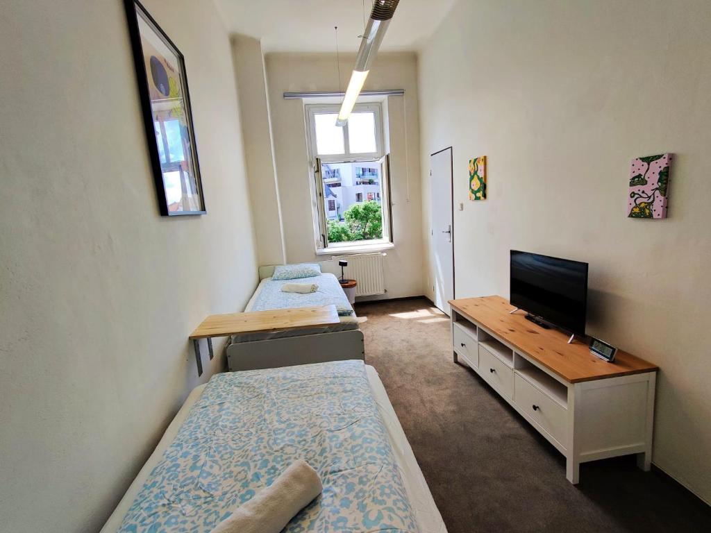 a room with two beds and a tv and a desk at Cozy Flat at Žižkov & Free Parking in Prague