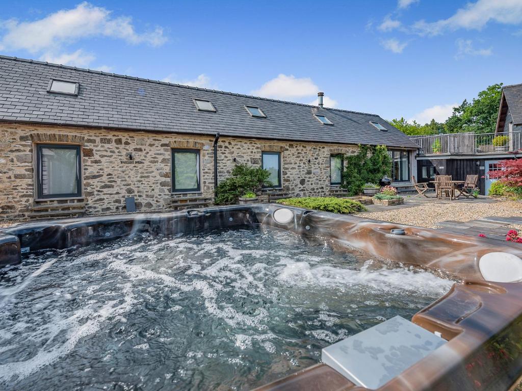 a swimming pool in front of a house at West Barn in Llansadwrn