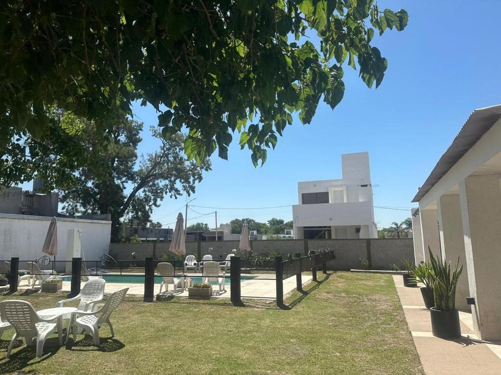 einen Garten mit Stühlen, Tischen und einem Pool in der Unterkunft Monoambiente acogedor cerca de playa en Miramar in Miramar