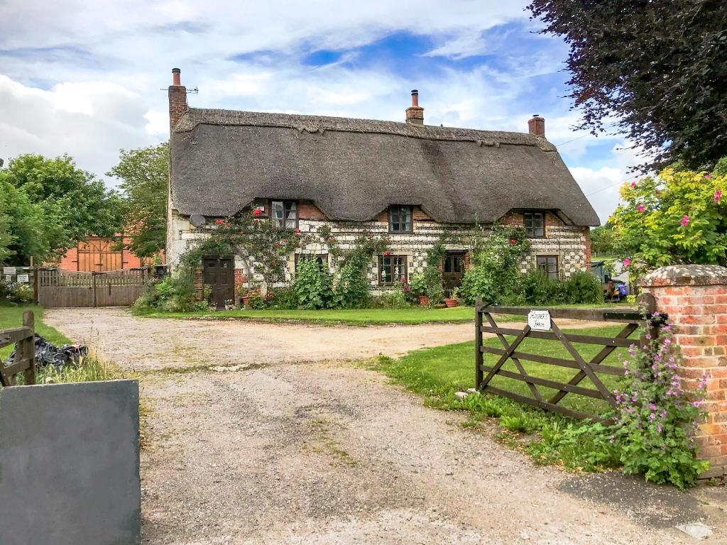 een oud stenen huis met een rieten dak bij Hoopers Farmhouse - Uk36307 in Tilshead