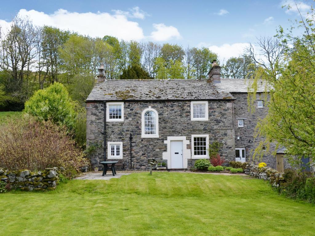 una antigua casa de piedra con un patio de césped en High Birch Close, en Penruddock