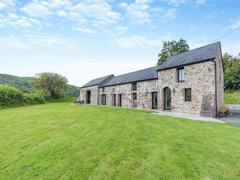 an old stone house with a large grass yard at Y Stabl in Llanwrda