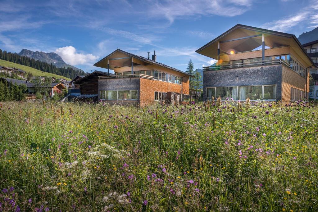 une maison au milieu d'un champ de fleurs dans l'établissement Design Chalets Lech, à Lech am Arlberg