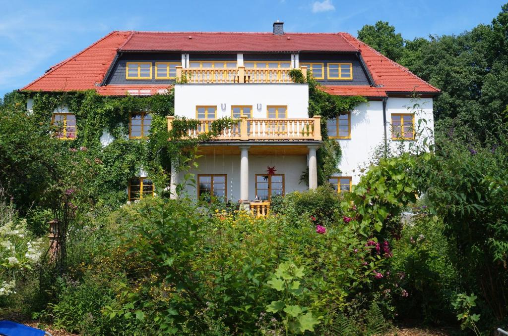 ein großes weißes Haus mit rotem Dach in der Unterkunft Ökopension Villa Weissig in Struppen