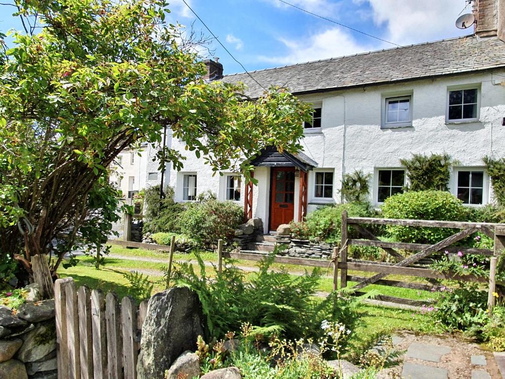 a white house with a red door and a fence at Garden Cottage in Threlkeld