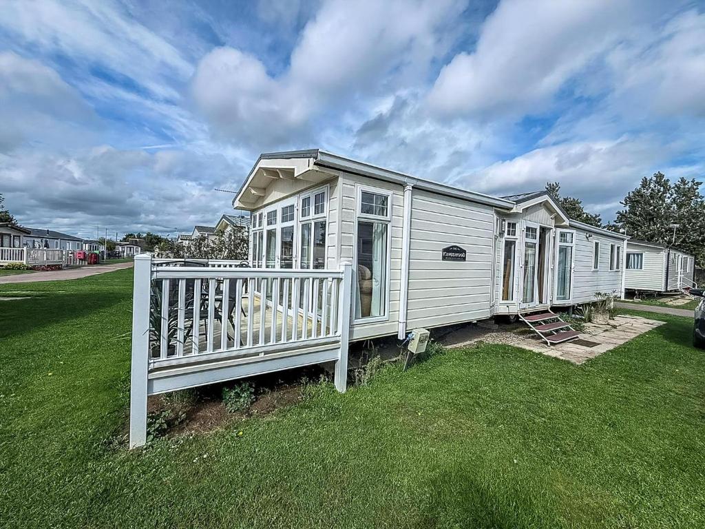 a white house with a fence in the grass at 6 Berth Caravan For Hire At California Cliffs In Scratby By The Beach Ref 50050L in Great Yarmouth