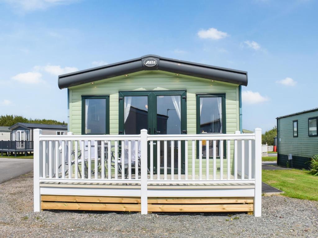 a green tiny house with a white fence at Peachy in Heysham