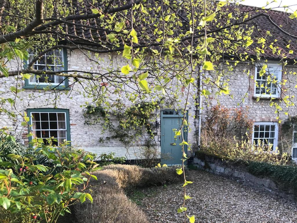 une maison en pierre avec une porte et des fenêtres vertes dans l'établissement Lavender Cottage, à Methwold
