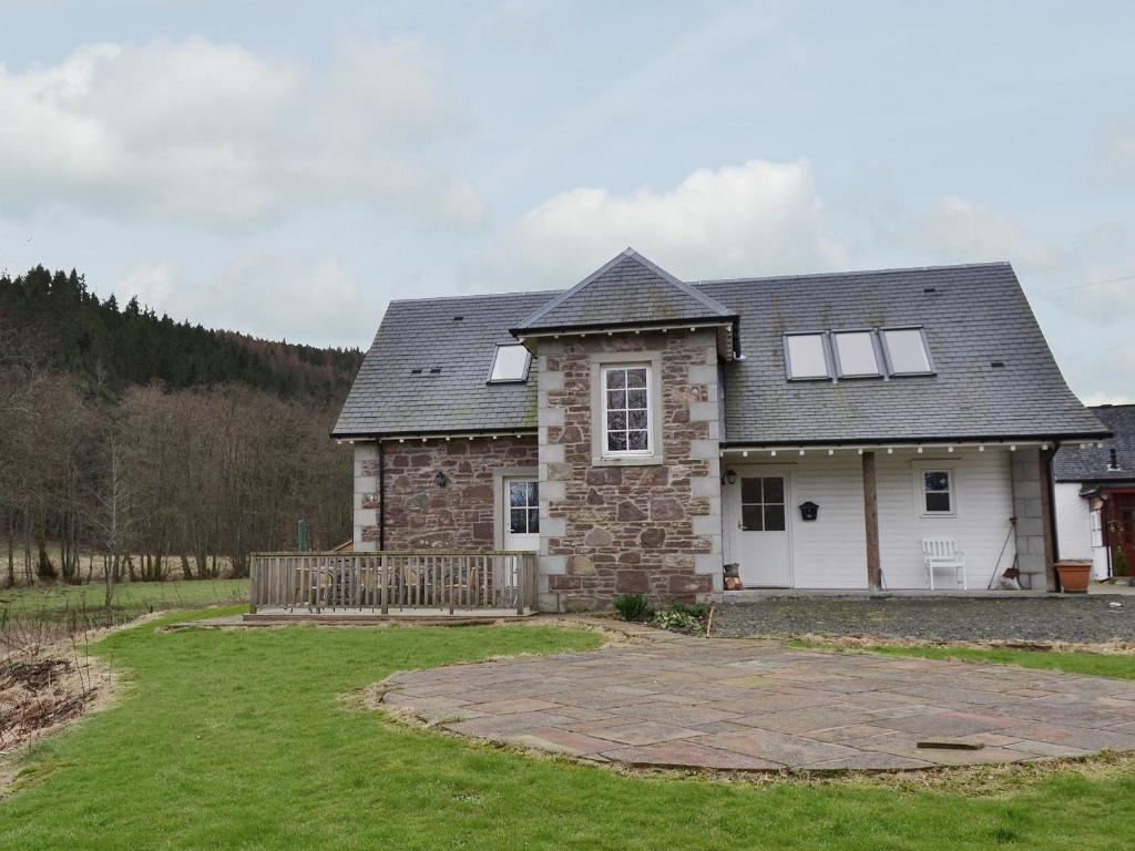 a large stone house with a yard at Mill Cottage in Comrie