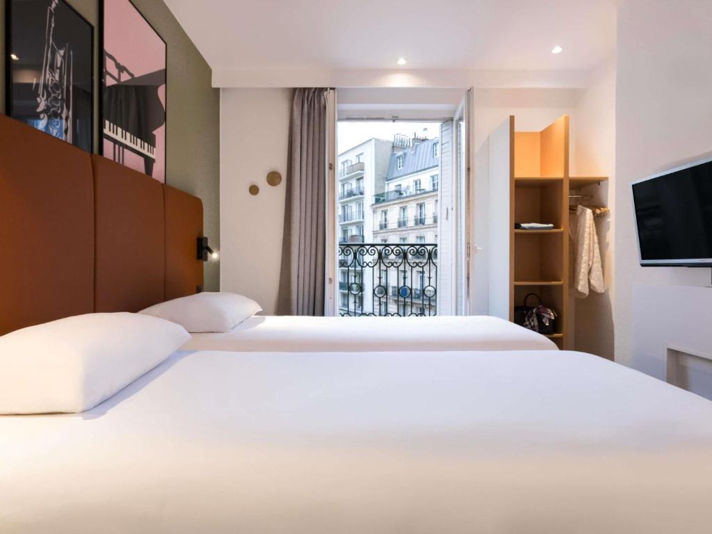 a bedroom with two white beds and a window at ibis Paris Gare du Nord TGV in Paris
