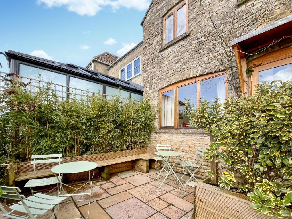 a patio with tables and chairs in front of a building at Drovers Cottage in Tetbury