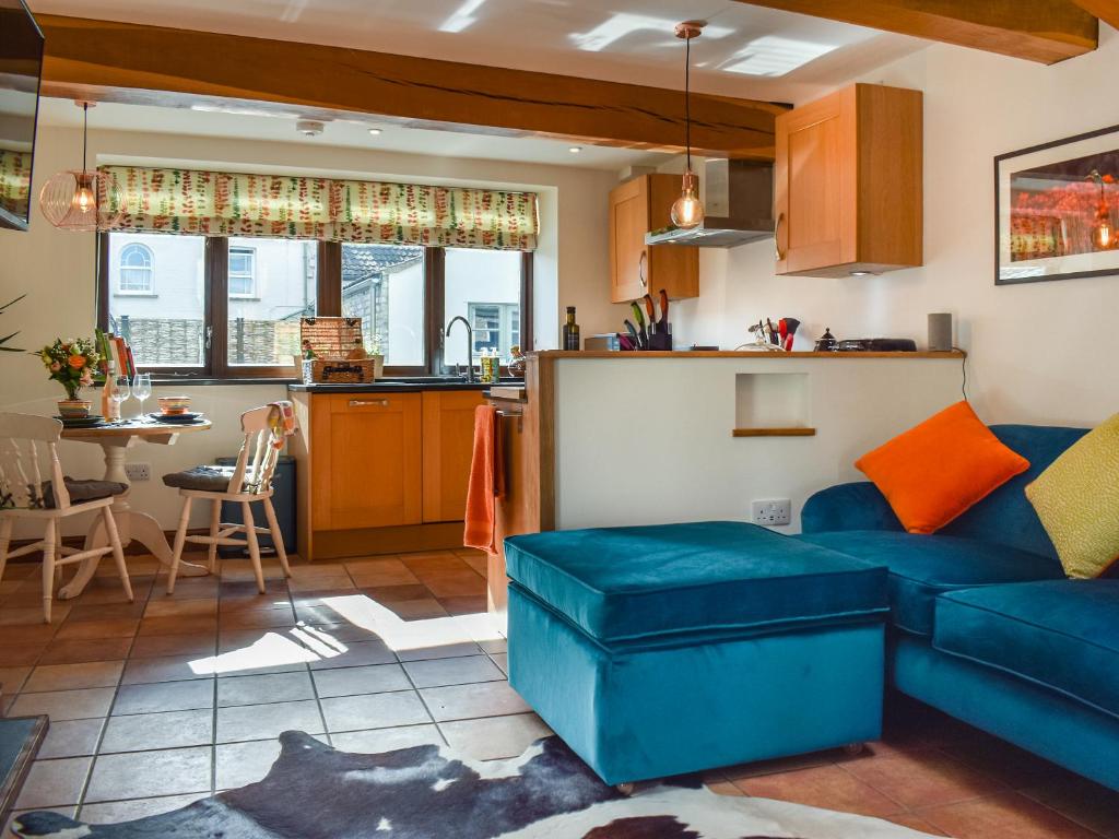 Una sala de estar con un sofá azul y una cocina. en Katy, en Meare