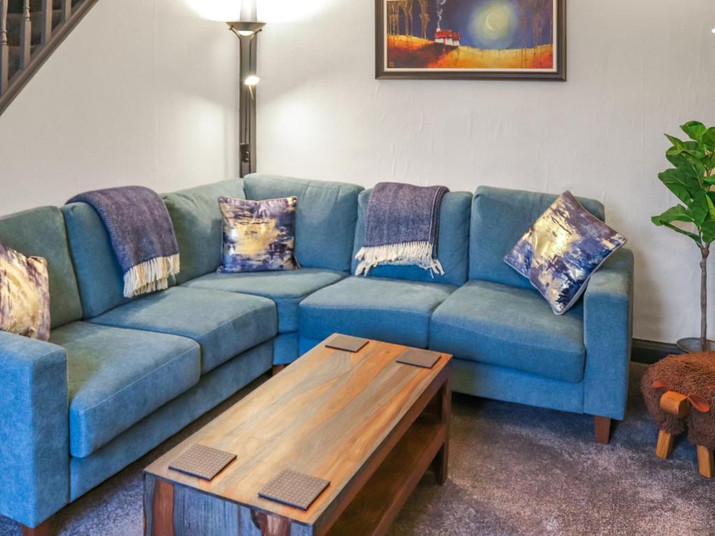 Una sala de estar con un sofá azul y una mesa de café. en Hafanedd, en Dyffryn