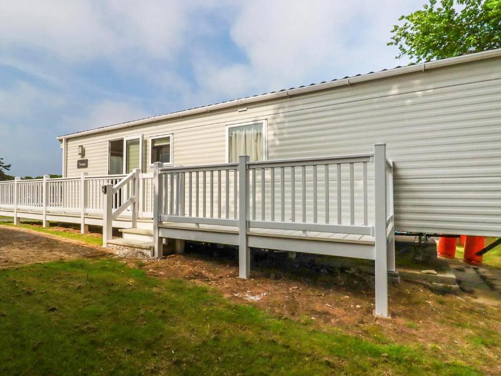 a white mobile home with a porch and a fence at 82 Hillside in Newquay