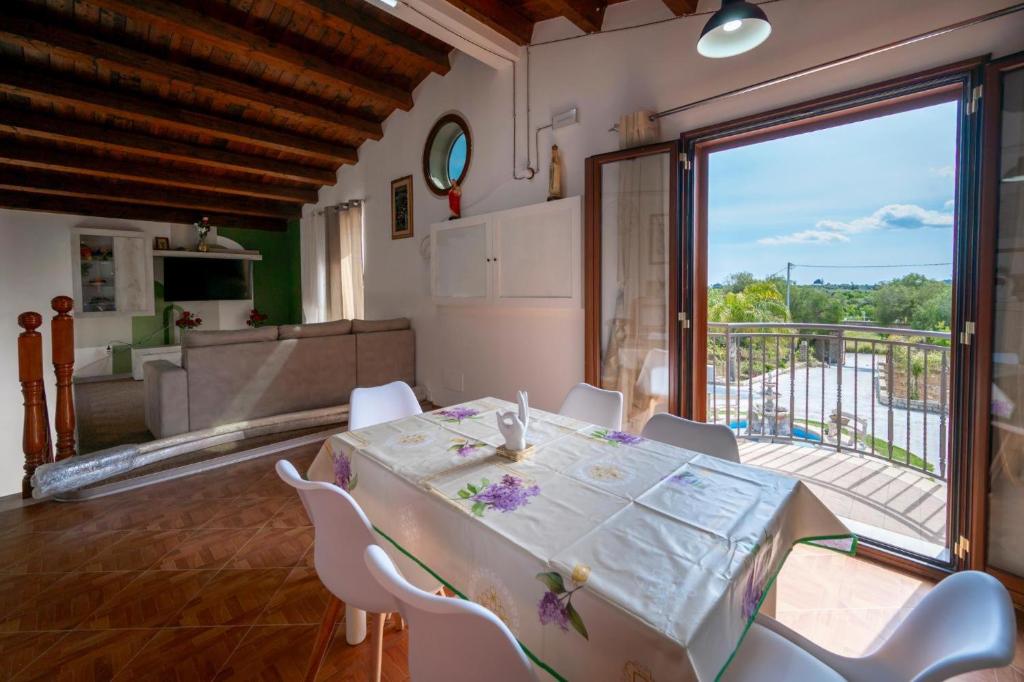 een eetkamer met een tafel en stoelen en een balkon bij Jungle Holiday Apartment in Marina dʼAvola