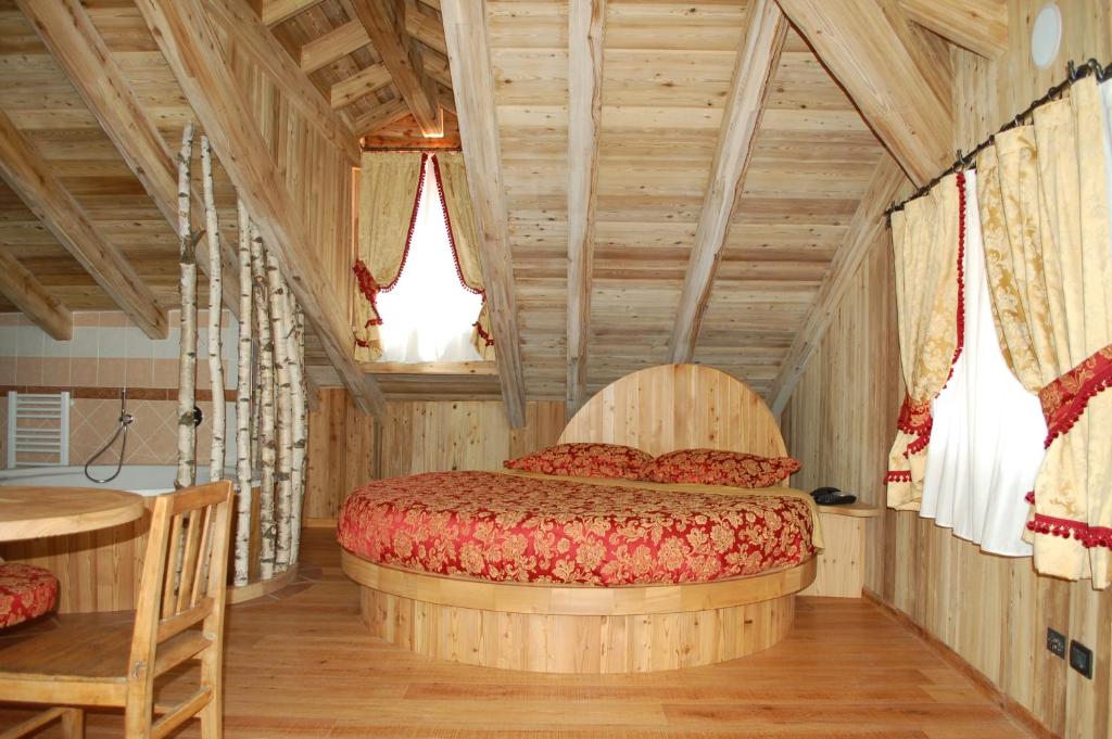 1 dormitorio con 1 cama en una habitación con techos de madera en Residenza La Corte Dei Toldi, en Terzolas