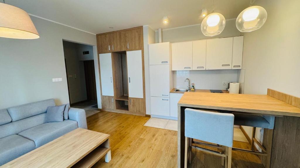 a kitchen and a living room with a blue couch at Apartamenty Bistro12 in Sokoły
