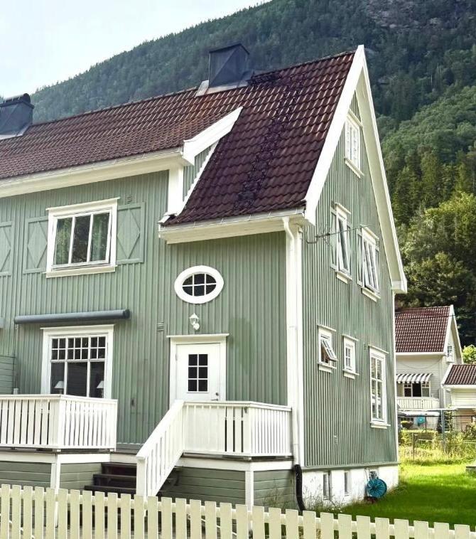 a green house with a wooden fence in front of it at Tveitopark Apartments B in Rjukan